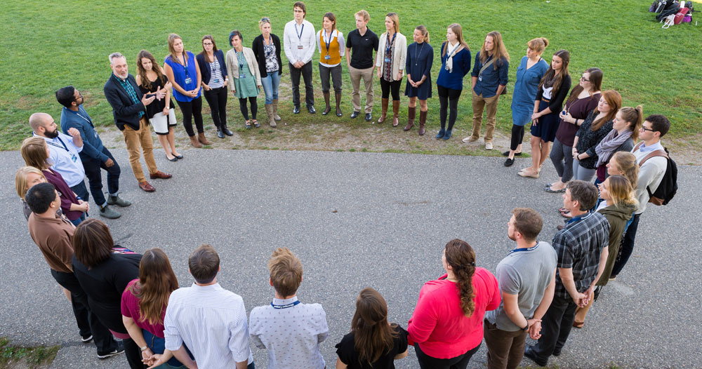 Group of people in big circle outside.