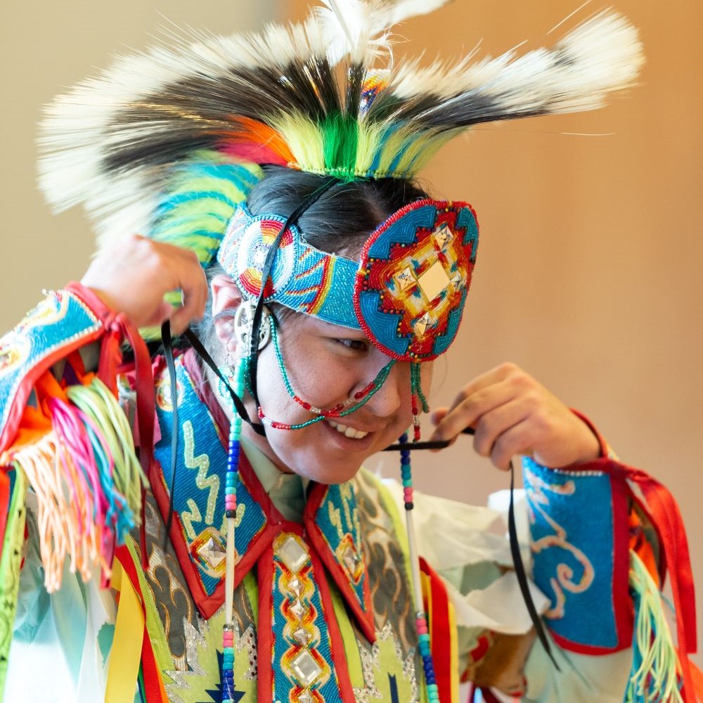 Colton wearing Indigenous regalia, smiling.