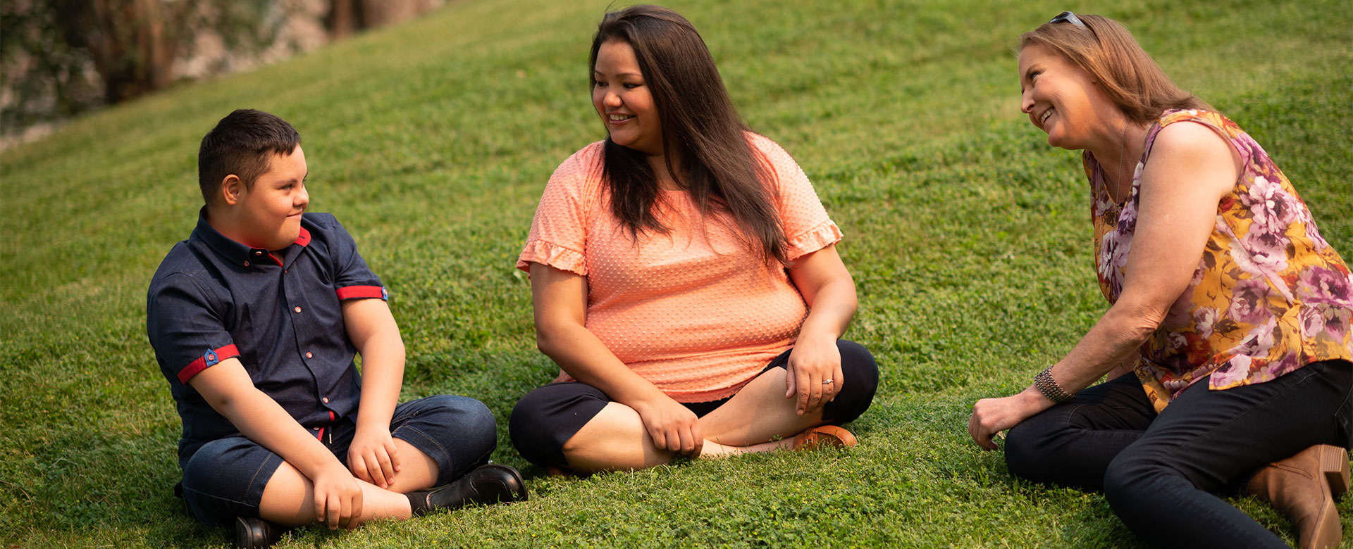 Candice and Jonah Loring sitting on grass with Rachelle Hole