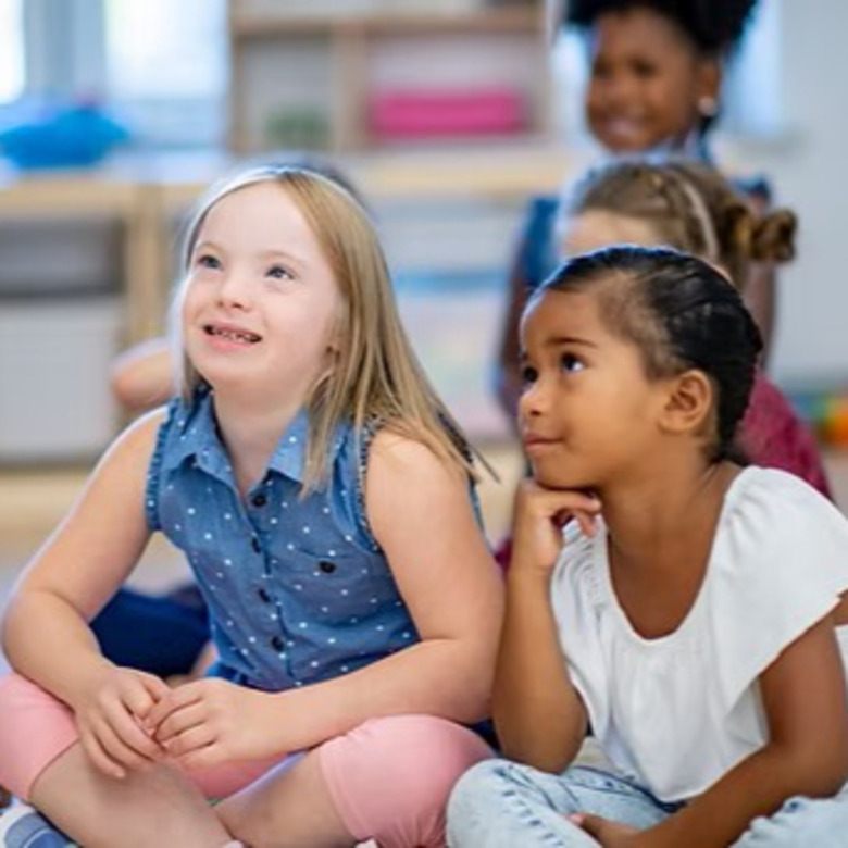 Children sitting crosslegged in classroom.